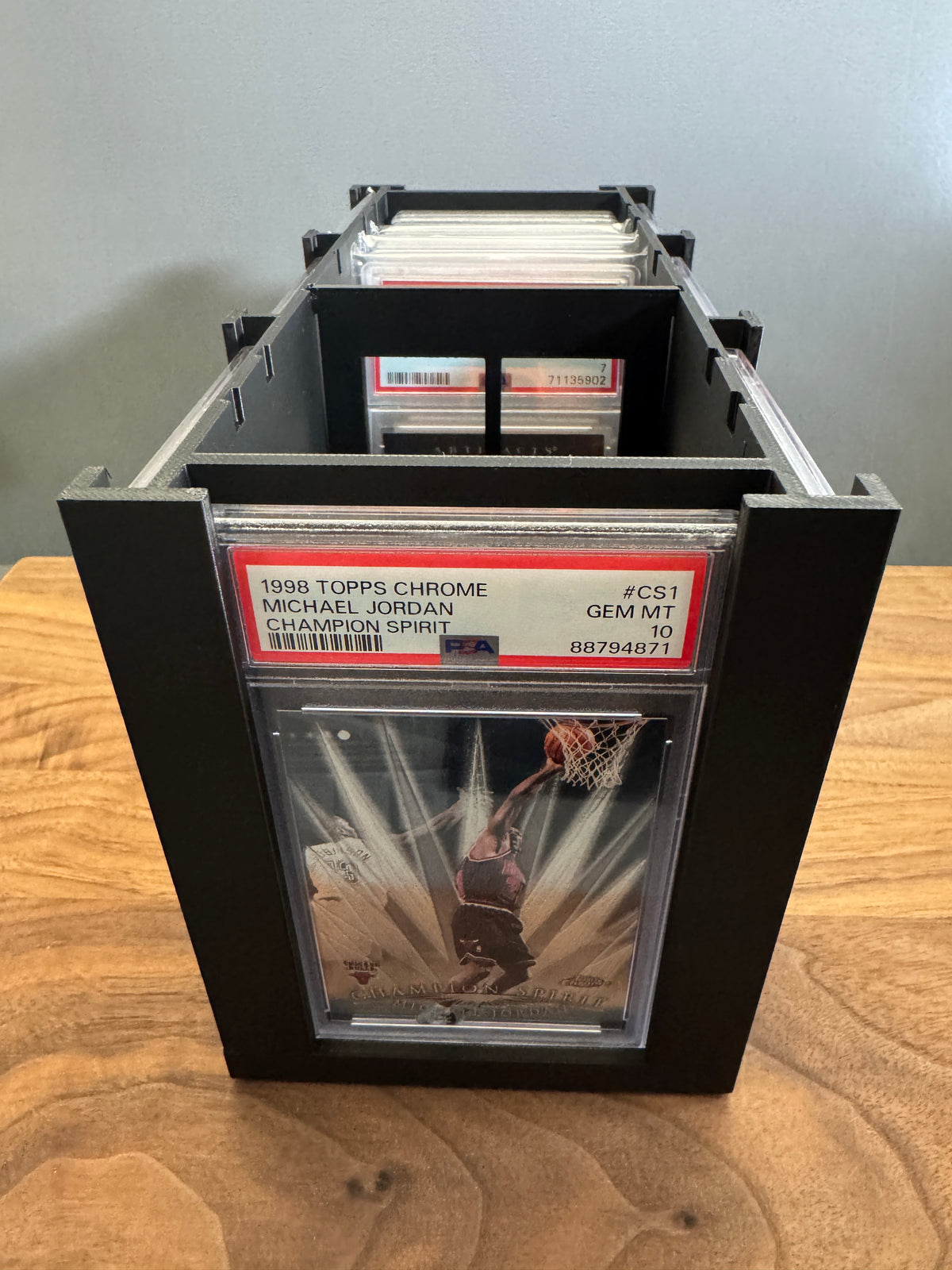 Looking down the length of the Slab Station Large graded card storage box with PSA slabs standing upright inside behind the display panel