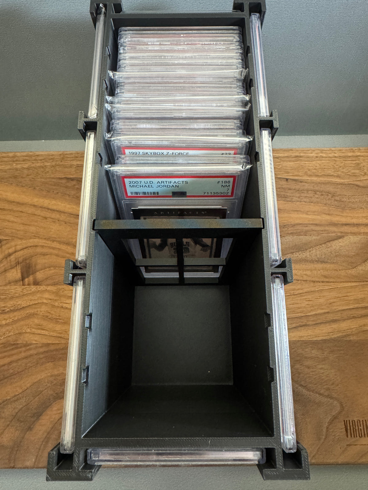 Top view inside the Slab Station Large showing about ten PSA graded slabs stored upright with the adjustable divider in a notched position