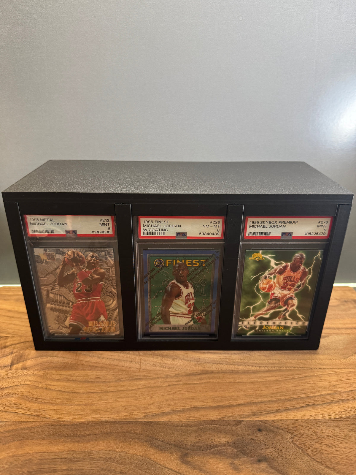 Large graded card display and storage box showing three PSA Michael Jordan slabs side by side in the front display windows