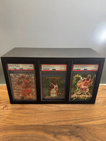 Large graded card display and storage box showing three PSA Michael Jordan slabs side by side in the front display windows